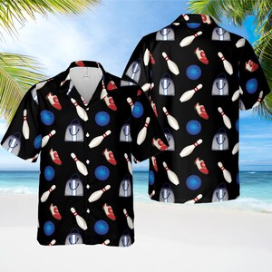 May include: Black short-sleeved button-down shirt with a bowling-themed pattern. The design includes white bowling pins, blue bowling balls, red bowling shoes, and gray tote bags. The shirt is a casual wear item.