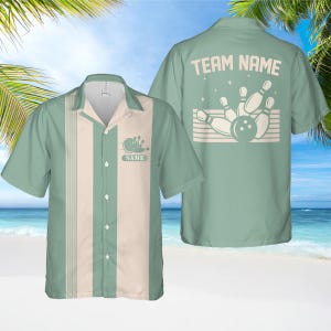 May include: A light green bowling shirt with a cream-coloured vertical stripe. The shirt has a bowling ball and pins graphic with the word "NAME" on the front and "TEAM NAME" on the back. Short-sleeved, ideal for a bowling team.