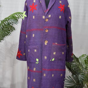 May include: A long purple quilted jacket with a shawl collar and button closure. The jacket has a geometric pattern and is decorated with embroidered flowers and leaves in red, green, and gold.