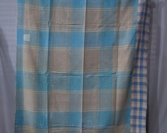 May include: A blue and beige plaid blanket with a white and blue plaid border. The blanket is woven and has a rustic, vintage look.