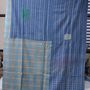 May include: A blue and white striped quilt with a patchwork design. The quilt features a combination of vertical stripes and plaid patterns in shades of blue and white. Patches of green and white fabric are sewn onto the quilt.