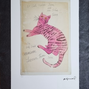 Könnte beinhalten: Eine rosa Katzenillustration mit dunkelrosa Streifen und orangefarbenen Augen, betitelt "25 Cats Name Sam and one Blue Pussy" von Andy Warhol. Das Kunstwerk enthält Signaturen und Text, präsentiert auf cremefarbenem Hintergrund mit weißem Rand.