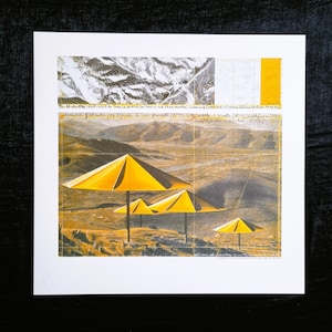 May include: A black and white print of a landscape with four yellow umbrellas. The print includes handwritten text that reads "The Umbrella Field project in the San Jacinto Desert, Los Angeles and the Mojave Desert, Southern California.  Distance 8.69 meters (28.5') side to side.  Gornets (28) with 3.3 meters (10.8') width.  3.3 meters (10.8') length of the 7.2 meters (23.6') section."