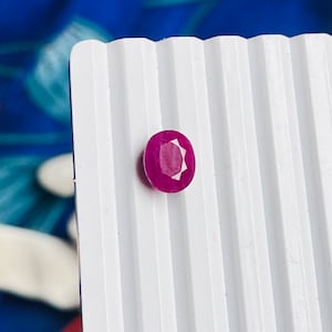 Könnte beinhalten: Ein tief roter Edelstein mit facettiertem Schliff. Der Edelstein ist rund und hat eine glänzende Oberfläche.