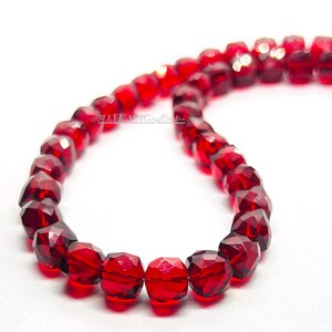 May include: A strand of red faceted glass beads. The beads are round and have a shiny finish.