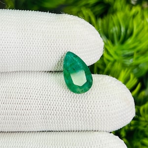 May include: A pear-shaped emerald gemstone with a green hue and a faceted cut.