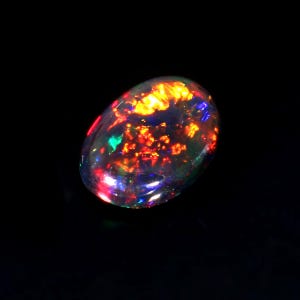 Könnte beinhalten: Ein schwarzer Opal-Edelstein mit einer leuchtenden Darstellung von irisierenden Farben in Rot, Orange, Grün und Blau.