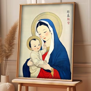 Może przedstawiać: Oprawiony wydruk obrazu religijnego przedstawiający kobietę w niebieskim welonie trzymającą dziecko. Obie postacie mają złote aureole. Kobieta ma na sobie czerwoną suknię. Wydruk jest w drewnianej ramie i jest wystawiony na drewnianym stole.