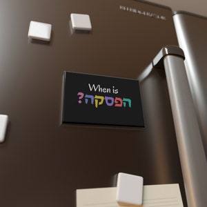 May include: A black refrigerator magnet with the text "When is Hanukkah?" in Hebrew and English. The Hebrew text is in colorful letters.