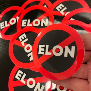 May include: A stack of round red and black stickers with a diagonal red line through the center. The stickers have the word "ELON" printed in white letters.