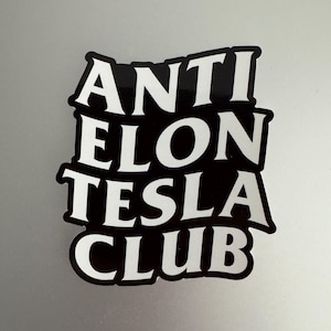 May include: Black and white sticker with the text "ANTI ELON TESLA CLUB" in a bold, stylized font.