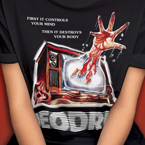 May include: Black t-shirt with a graphic of a television set and a hand reaching out from the screen. The text "First it controls your mind then it destroys your body" is printed on the shirt.