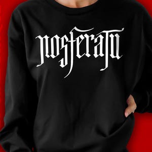 May include: Black sweatshirt with white text that reads "Nosferatu" in a gothic font.