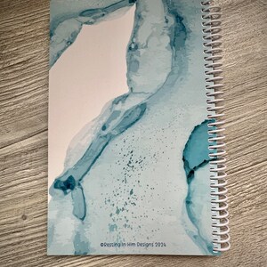 Peut inclure: Un carnet &agrave; spirales bleu et blanc avec un motif aquarelle abstrait. La couverture pr&eacute;sente un motif aquarelle bleu clair et blanc sur fond blanc. Le texte "&copy;Resting in Him Designs 2024" est imprim&eacute; dans le coin inf&eacute;rieur droit de la couverture.