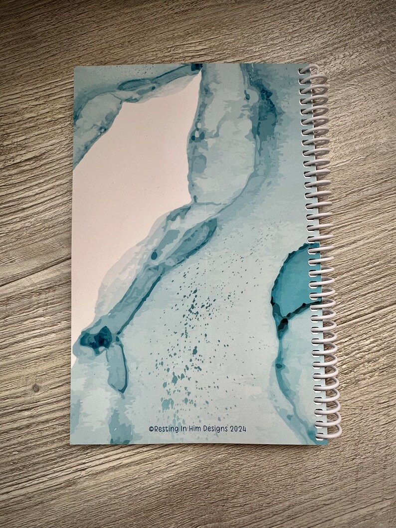 Peut inclure: Un carnet &agrave; spirales bleu et blanc avec un motif aquarelle abstrait. La couverture pr&eacute;sente un motif aquarelle bleu clair et blanc sur fond blanc. Le texte "&copy;Resting in Him Designs 2024" est imprim&eacute; dans le coin inf&eacute;rieur droit de la couverture.