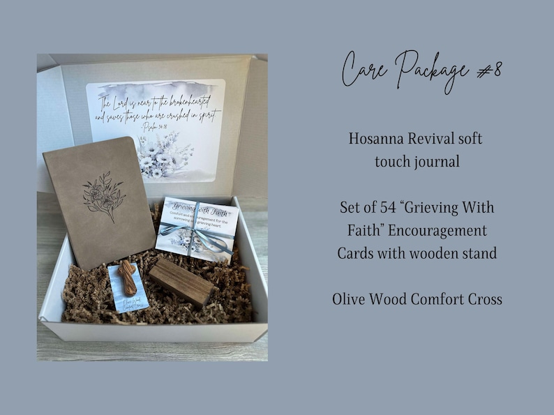 May include: A white gift box filled with a brown journal, a set of 54 encouragement cards, a wooden stand, and a small olive wood cross. The box lid has a floral design and the text "The Lord is near to the brokenhearted and saves those who are crushed in spirit."  Psalm 34:18