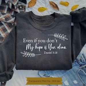 以下が含まれることがあります： 白い文字で「Even if you don't My hope is You alone. Daniel 3:18」と書かれた濃いグレーのスウェットシャツ。テキストは小さな白い花の模様で囲まれています。