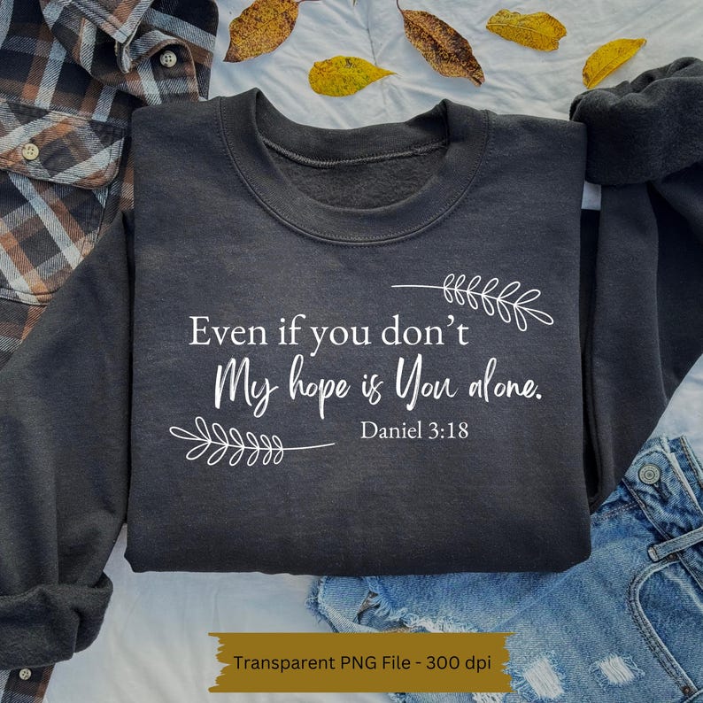 May include: A dark grey sweatshirt with the text "Even if you don't My hope is You alone. Daniel 3:18" in white lettering. The text is surrounded by small white floral designs.