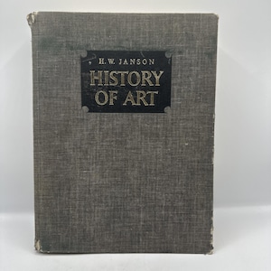 May include: A hardcover book titled "History of Art" by H.W. Janson. The book has a gray textured cover with the title and author's name in gold lettering on a black rectangular label. The book's edges show signs of wear.