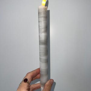 May include: A white and gray striped candle with a flickering flame.