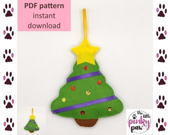 May include: A felt Christmas tree ornament with a yellow star on top, purple ribbon, and red and gold sequins. The ornament is green and brown and has a loop for hanging. The text "the little pinky paw" is visible in the bottom right corner.