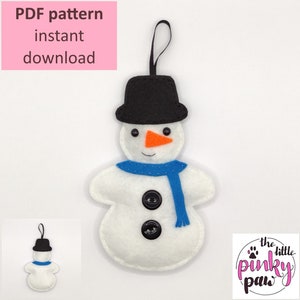 May include: PDF pattern for a felt snowman ornament. The snowman is white with a black hat, blue scarf, and orange nose. The pattern includes two buttons and a black loop for hanging. The pattern is available for instant download. The image also includes the text "the little pinky paw".