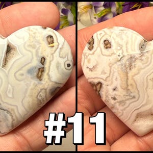 May include: Two heart-shaped stones with a swirling pattern of white, gray, and brown. The stones are held in a hand, and the number "#11" is displayed in the lower right corner. The stones have a polished surface.
