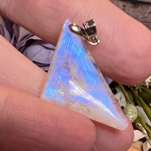 May include: A triangular iridescent moonstone pendant with a silver bail. The stone has a white base with blue and purple iridescent flashes.