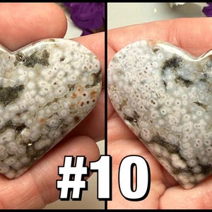 May include: Two heart-shaped stones with a polished surface. The stones have a mix of white, gray, brown, and green patterns. The text "#10" is displayed in the lower center of the image. The stones are held in a person's hands.