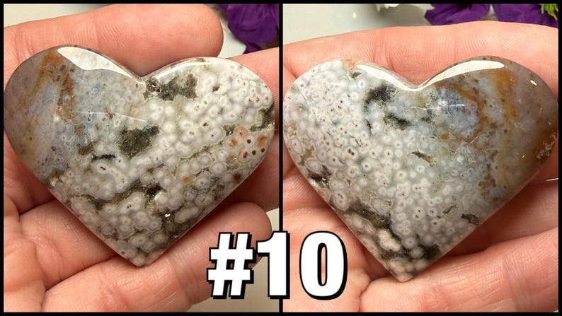 May include: Two heart-shaped stones with a polished surface. The stones have a mix of white, gray, brown, and green patterns. The text "#10" is displayed in the lower center of the image. The stones are held in a person's hands.