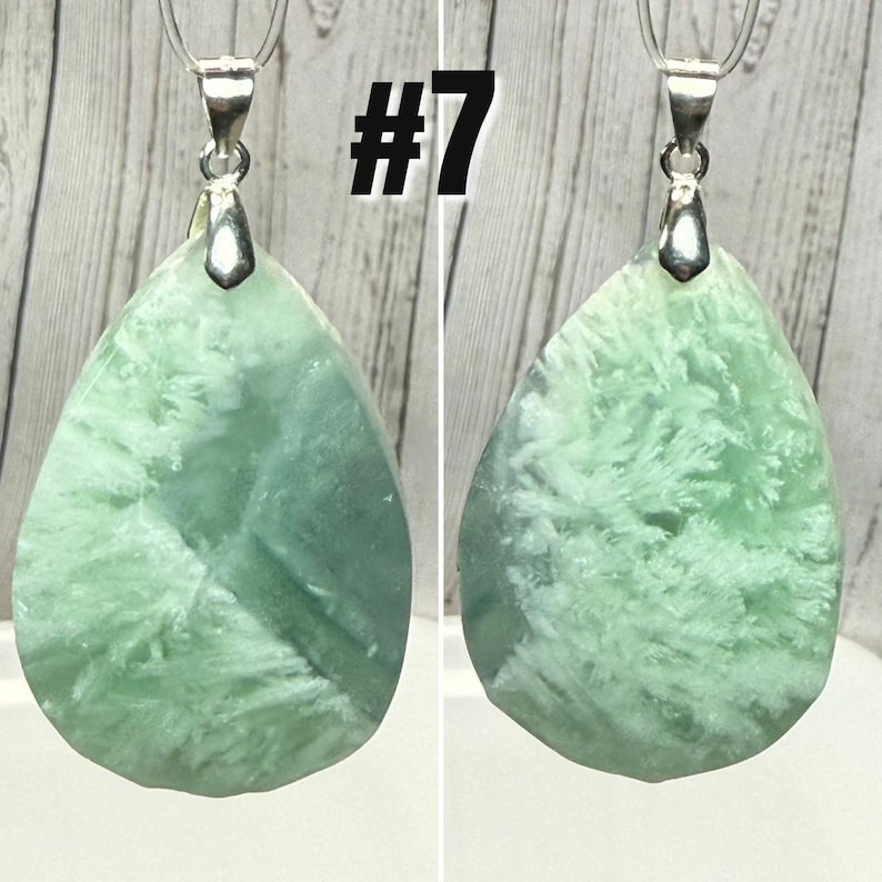 May include: Two teardrop-shaped pendants with a light green and white pattern. Each pendant is attached to a silver-coloured bail and chain. The number "#7" is printed in black on the top of the image.