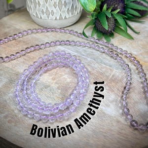 May include: Two strands of light purple Bolivian Amethyst beads. The larger strand is a necklace and the smaller strand is a bracelet.