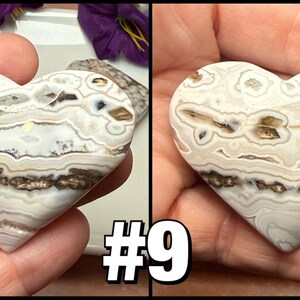 May include: Two heart-shaped stones with a white, brown, and gray patterned design. The stones are held in a person's hand. The image includes the text "#9" in white with a black outline.
