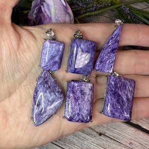 May include: Six purple and silver pendants with a variety of shapes and sizes. The pendants are made of a shimmering, iridescent material.