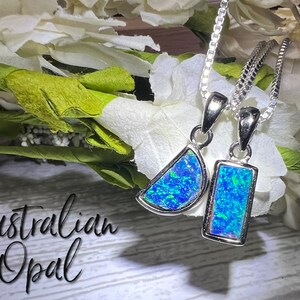 May include: Two silver necklaces with blue Australian opal pendants. One pendant is a half-moon shape and the other is a rectangular shape.