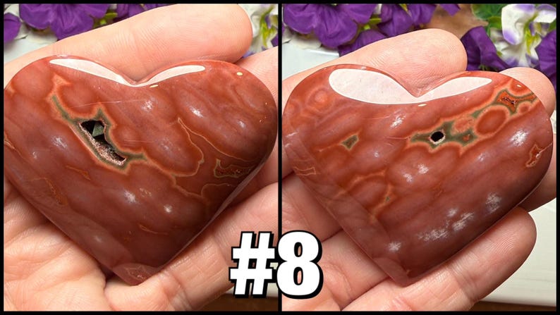 May include: A polished, heart-shaped stone with a reddish-brown hue and white veining. The stone has a natural cavity with green and white accents. The number "#8" is displayed in a white font with a black outline.