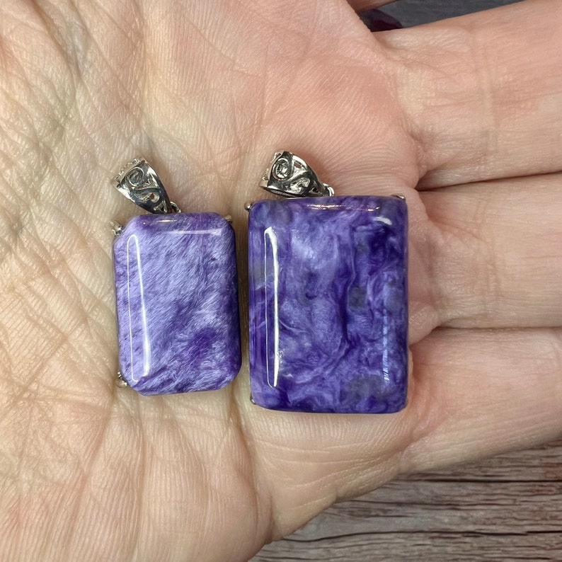 May include: Two purple and silver pendant charms with a swirling pattern. The larger charm is about 2 inches long and the smaller charm is about 1.5 inches long.