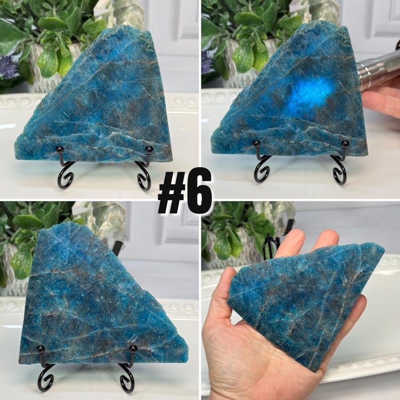 May include: A blue apatite crystal slice, triangular in shape, displayed on a black metal stand. The stone has a rough texture with shades of blue and brown. The number "#6" is visible in the image.