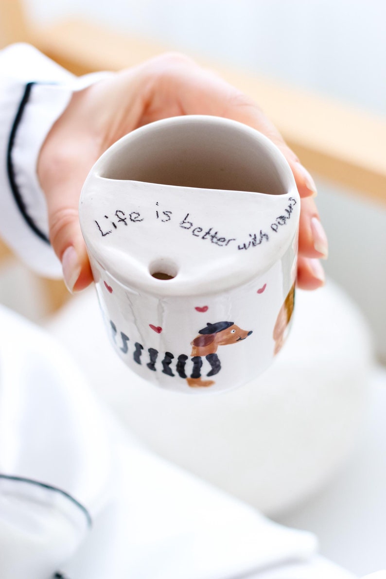 May include: White ceramic mug with a dachshund illustration and the text "Life is better with paws".