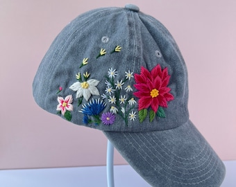May include: A grey denim baseball cap with embroidered flowers in shades of pink, red, white, blue and yellow.