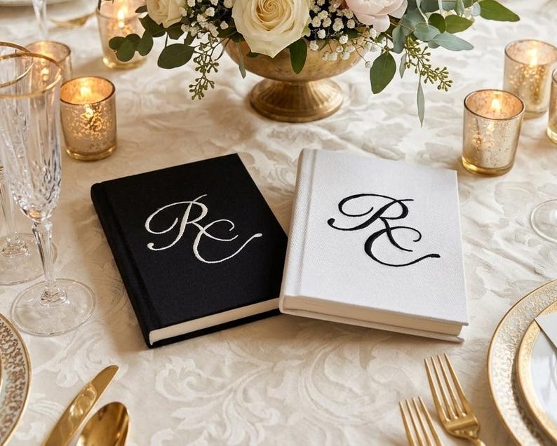 Pode incluir: Dois livros de capa dura com revestimento em tecido, um preto com letras de monograma RC bordadas em branco e um branco com letras de monograma RC bordadas em preto. Os livros s&atilde;o retangulares com uma lombada limpa e acabamento texturizado.