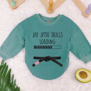 May include: A teal blue long-sleeved sweatshirt with the text "Jiu Jitsu Skills Loading" and a black belt with a red stripe. The progress bar is almost full.