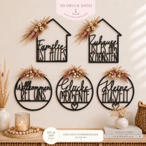 May include: Five black wall-mounted signs with house and circle frames, featuring German text including Familie ist alles, Zuhause ist es am schönsten, Willkommen bei uns, Glücks Momente, and Kleine Auszeit, decorated with dried flowers and grasses.