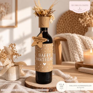 May include: A dark glass wine bottle wrapped in a tan paper sleeve featuring white polka dots and the text HAPPY BIRTHDAY. A star-shaped wooden tag hangs from the neck with the text Eine KLEINIGKEIT für dich and a heart icon.