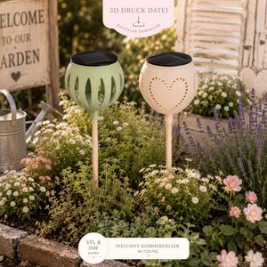 May include: Two solar garden lights on wooden stakes, one sage green with vertical cutouts and one cream with a heart-shaped cutout pattern. Each light features a black solar panel on top. The text 3D DRUCK DATEI DIGITALER DOWNLOAD and STL & 3MF DATEI INKLUSIVE KOMMERZIELLER NUTZUNG is visible.