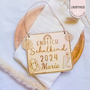 Puede incluir: Un letrero de madera con el texto "ENDLICH SCHULKIND 2024 Maria" y un arcoíris, una mochila y un lápiz. El letrero está decorado con flores.