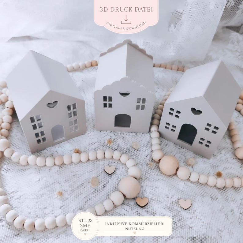 May include: Three small, light grey house-shaped decorations with cut-out windows and doors. Each house has a different roof design. The houses are surrounded by a beaded garland and small wooden hearts. Text on the image reads "3D Druck Datei" and "Digitaler Download".