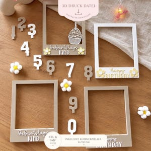 Può includere: Tre cornici portafoto rettangolari in bianco e beige, accompagnate da numeri individuali da zero a nove. Le cornici presentano scritte tra cui "Geburtstags Kind" e "Happy Birthday", insieme a decorazioni a forma di cupcake e fiori.