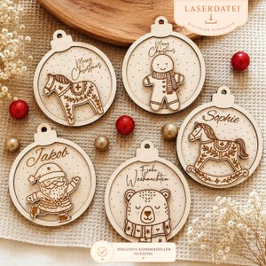 Puede incluir: Adornos navideños de madera con varios diseños, incluyendo un caballo, hombre de jengibre, Papá Noel, oso y caballito balancín. Cada adorno tiene forma circular con un lazo para colgar. Los adornos son de color marrón claro con detalles grabados.