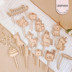 May include: A selection of wooden cake toppers featuring animal designs such as a fox, dog, and cat, alongside birthday-themed elements. The toppers are light brown and laser-cut with detailed designs. Some toppers include the text "Happy Birthday."